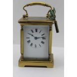 A BRASS FRAMED CARRIAGE CLOCK, with bevelled glass panels, white enamel dial with Roman numerals,