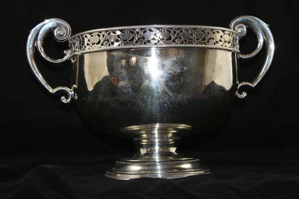 A SILVER PLATED BOWL with pierced rim and scroll terminal handles on circular platform foot, 23cm