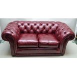 A LATE 20TH CENTURY DISTRESSED OX BLOOD LEATHER UPHOLSTERED BUTTON BACKED TWO PERSON CHESTERFIELD