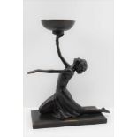 AN ART DECO STYLE DANCING LADY, ebonised, upon a plinth, holding aloft a bowl, bears the mark "