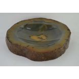 A POLISHED STONE DISH, oval depression, the edge of natural, irregular form 16cm x 14cm