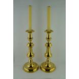A PAIR OF LATE VICTORIAN BRASS CANDLESTICKS, with pushrods, on domed circular bases, 31cm high