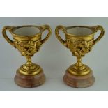 A PAIR OF 20TH CENTURY COMPOSITION GOBLET FORM URNS, of twin handle form, moulded with putti and