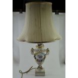 A CONTINENTAL CERAMIC TABLE LAMP, of urn form, decorated with ram's head mounts, floral encrusted,