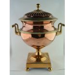 AN EARLY 19TH CENTURY COPPER & BRASS URN, with cover, fitted a pair of handles on a square base with