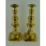 A PAIR OF 19TH CENTURY BRASS CANDLESTICKS, turned stems on canted square bases, 28cm high