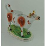 A 19TH CENTURY STAFFORDSHIRE POTTERY COW CREAMER with gilded horns, on groundwork base