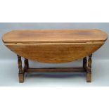A 20TH CENTURY OAK COFFEE TABLE, of drop leaf design, raised on turned supports with plain