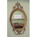 A REGENCY DESIGN GILT FRAMED MIRROR, urn finial with bell husk swags, oval bevel plate, 53cm x 37cm,