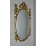 A DECORATIVE BRASS FRAMED WALL MIRROR, oval mirror plate, 69cm x 44cm