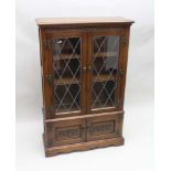 AN OAK DISPLAY CABINET, fitted two leaded glass doors over two panelled doors below, 80cm x 28cm x