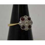 A RUBY AND DIAMOND CLUSTER RING, the central brilliant cut diamond bordered by four rubies and