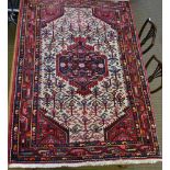 AN IRANIAN WOOL RUG, cream ground, with central stylised floral panel deeply bordered in red,