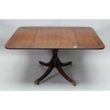 A REGENCY DESIGN MAHOGANY DROP LEAF DINING TABLE, on turned stem and four outswept brass paw