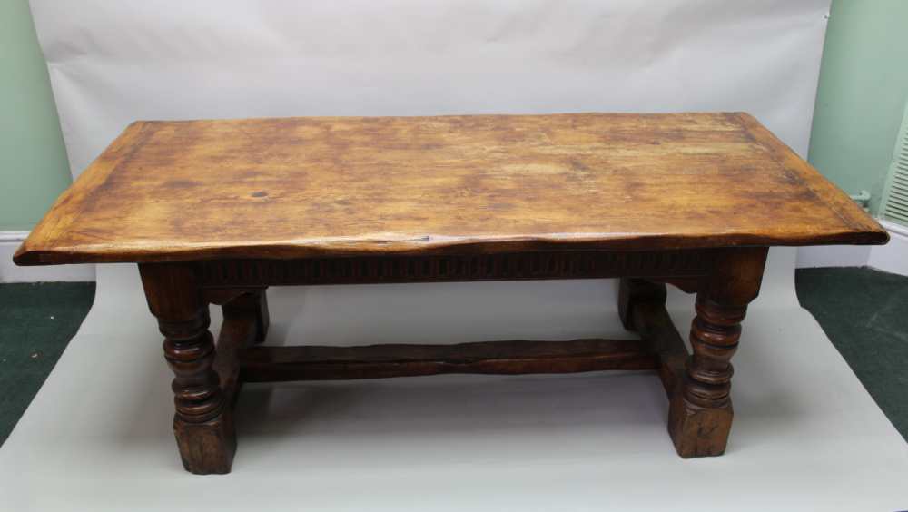 A 17TH CENTURY DESIGN OAK REFECTORY TABLE, having plank top on ring turned supports, with lunette