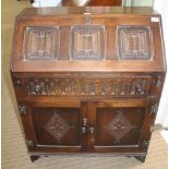 A SMALL REPRODUCTION OAK FINISHED BUREAU with linen fold panel front & turned acorn design knop