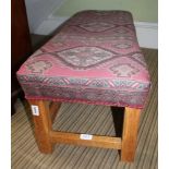 A DOUBLE WIDTH PADDED TOPPED FOOTSTOOL with kelim effect upholstery