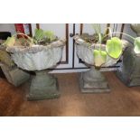 A PAIR OF WELL WEATHERED CAST CONCRETE CIRCULAR PEDESTAL BASED PLANTERS