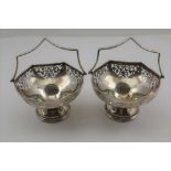 A PAIR OF SILVER SWEETMEAT BASKETS, pierced decoration, on circular bases with swing handles, London