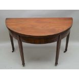 A 19TH CENTURY MAHOGANY DEMI-LUNE TEA TABLE, supported on four square tapering legs, terminating