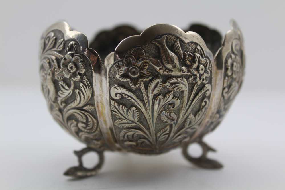 AN EASTERN WHITE METAL BOWL, of lobed form, decorated with birds amidst flowers, raised on three