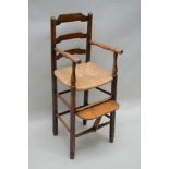 A 19TH CENTURY LADDER BACKED CHILD'S HIGH ARMCHAIR, with rush work seat, complete with footrest,