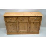 A 20TH CENTURY RECLAIMED PINE SIDEBOARD / DRESSER, having plain plank top with three inline