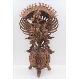 A 20TH CENTURY BALINESE WOOD CARVING, Vishnu riding the mythical Garuda bird, standing upon a floral