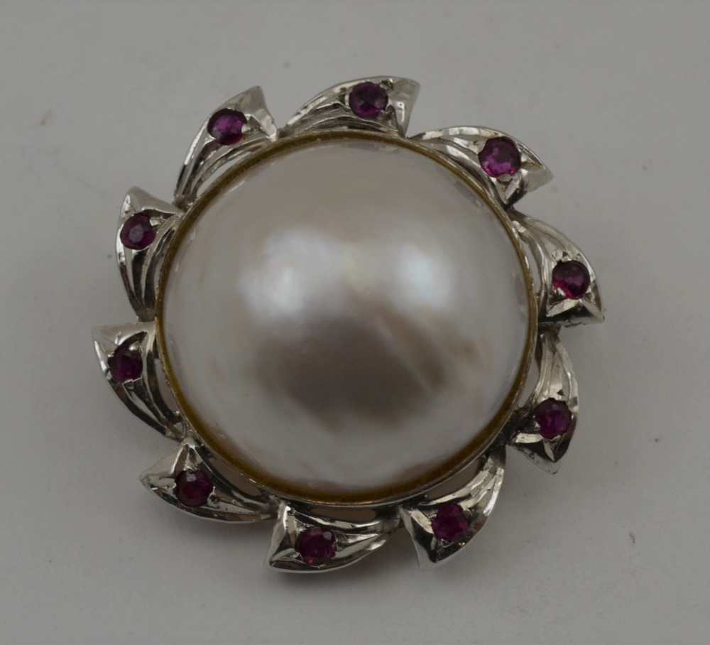 AN 18K WHITE GOLD BROOCH (set pendant hoop) with central pearl, the frame inset ten cut ruby
