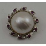 AN 18K WHITE GOLD BROOCH (set pendant hoop) with central pearl, the frame inset ten cut ruby