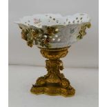 A CONTINENTAL CERAMIC BOWL upon a gilt brass base, the bowl with applied flowers, hand painted and