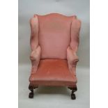 A 19TH CENTURY HIGH WINGED BACK ARMCHAIR, all over upholstered in raspberry corduroy, having