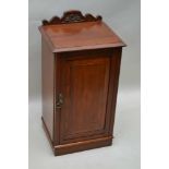 A 19TH CENTURY WALNUT FINISHED BEDSIDE POT CUPBOARD, having carved upstand, single panelled cupboard