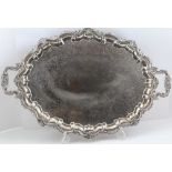 AN EPNS. TEA TRAY, of oval form with Rococo frame and two shell cast handles, raised on four
