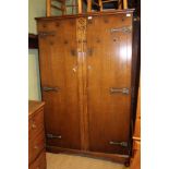 AN OAK TWO-DOOR WARDROBE with carved central panel and decorative metal furniture