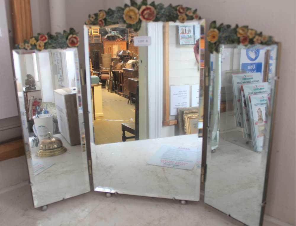 A FOLDING TRIPLE PLATE BEVEL DRESSING TABLE MIRROR with floral crest