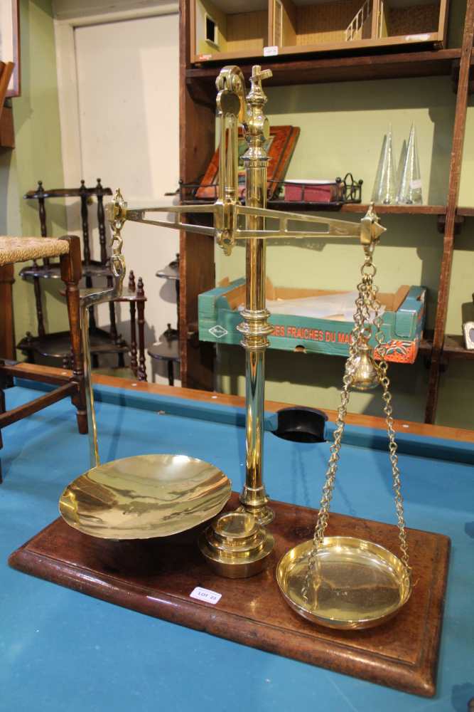 A 19TH CENTURY POLISHED BRASS SET OF BALANCE SCALES supported on a rectangular wooden plinth base,