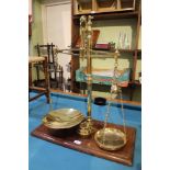 A 19TH CENTURY POLISHED BRASS SET OF BALANCE SCALES supported on a rectangular wooden plinth base,
