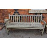 A WELL-WEATHERED TEAK SLAT BUILT THREE PERSON GARDEN BENCH