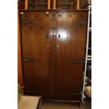 AN OAK FINISHED TWO DOOR WARDROBE with carved central panel and decorative metalwork