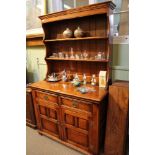 A STAINED OAK FINISHED DRESSER with twin shelf plate rack back, the base unit having two inline