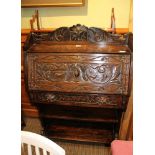 A LATE 19TH CENTURY CARVED OAK FRONTED STUDENT'S DESK with open book shelf base