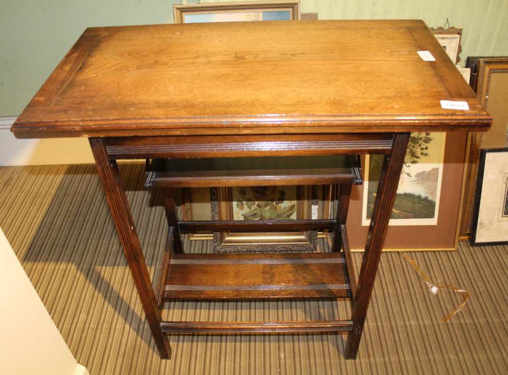 AN OAK FINISHED SWIVEL TOPPED FOLDING CARD TABLE, having folding undertier