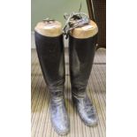 A PAIR OF BLACK LEATHER RIDING BOOTS with spurs, supported on wooden shoe trees
