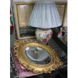 A FANCY GILT FRAMED OVAL BEVEL PLATE WALL MIRROR together with a rose decorated ceramic base table