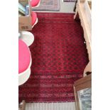 A PIGEON RED GROUND WOVEN WOOLEN CARPET with a busy geometric central field and multi-guard borders