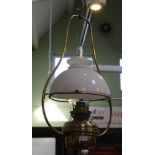 A HANGING BRASS OIL LAMP with milk glass shade