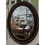 AN EARLY 20TH CENTURY OVAL BEVEL PLATE WALL MIRROR in fancy wooden frame, with applied cast gilt