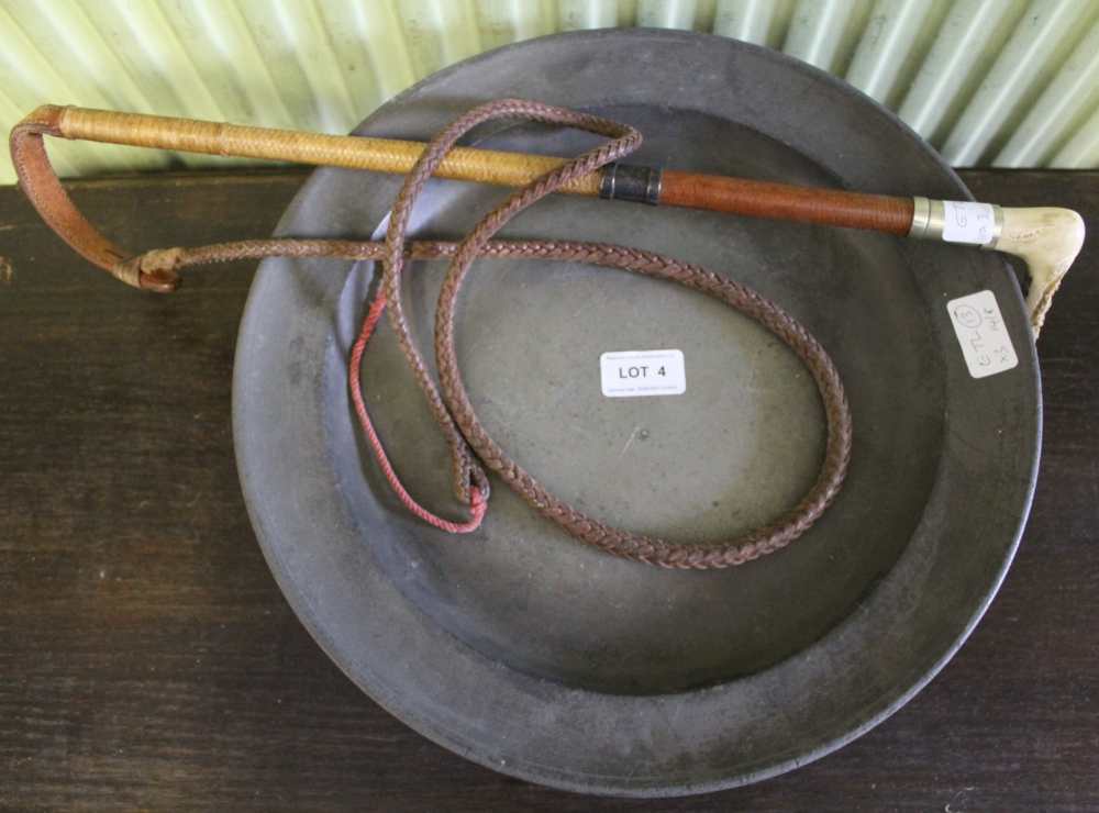 A PLAITED LEATHER WHIP with horn handle, together with two antique pewter dishes