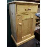 A PINE BEDSIDE UNIT with single drawer over cupboard door
